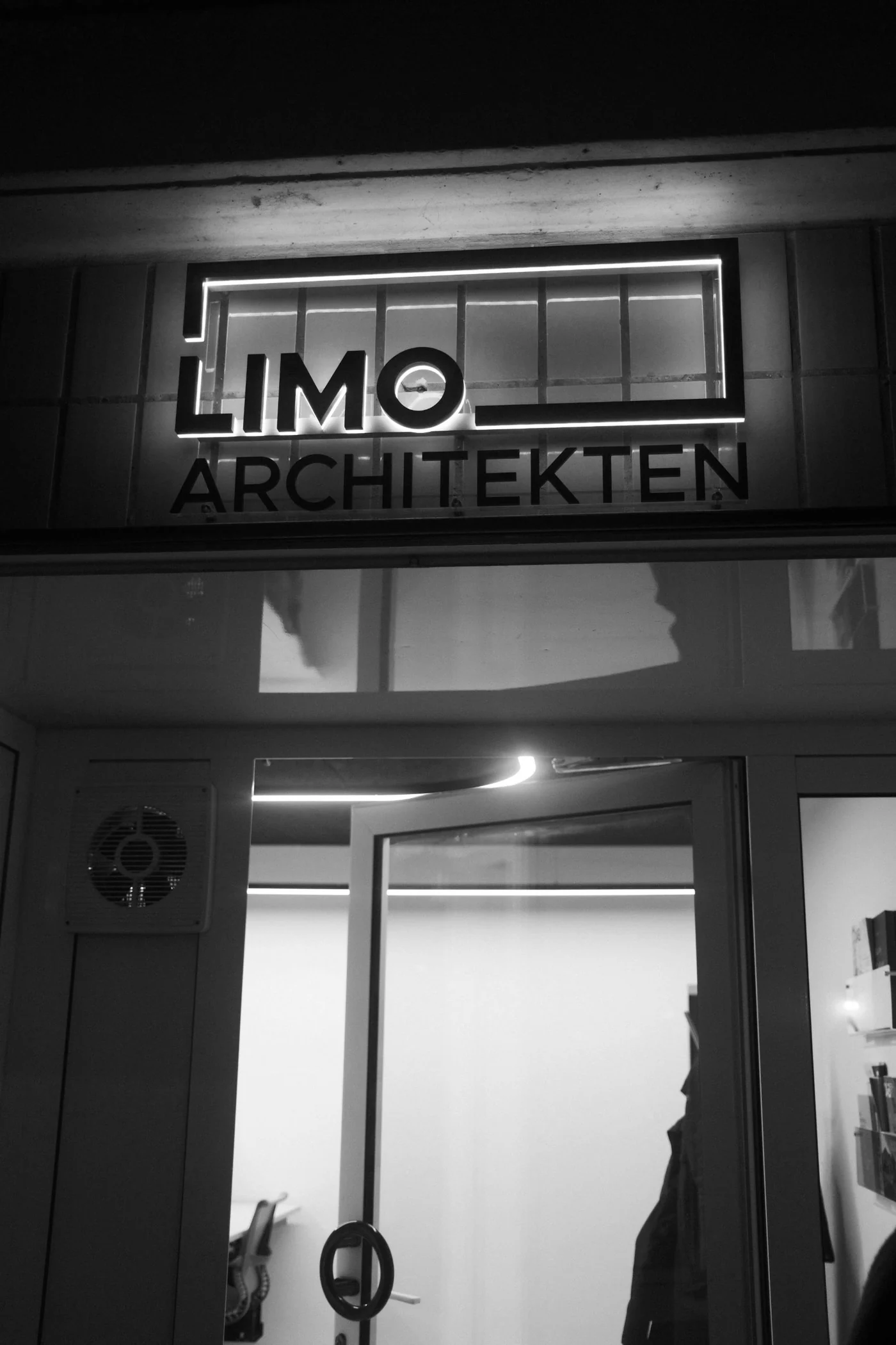 Beleuchtetes LIMO-Logo über dem Eingang des Büros bei Nacht